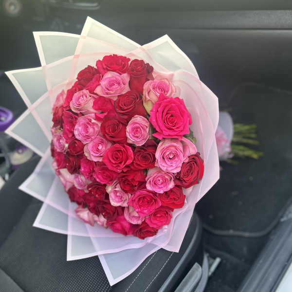 Bouquet of pink and red roses wrapped in translucent paper