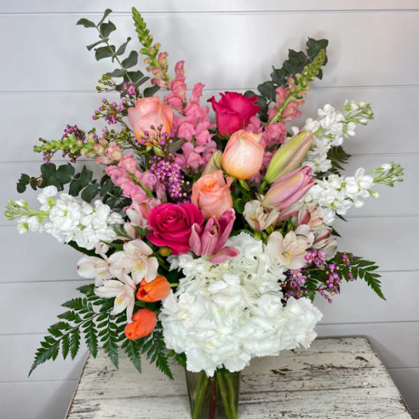 Tall pink and white mixed flower arrangement with roses and lilies in a clear glass vase