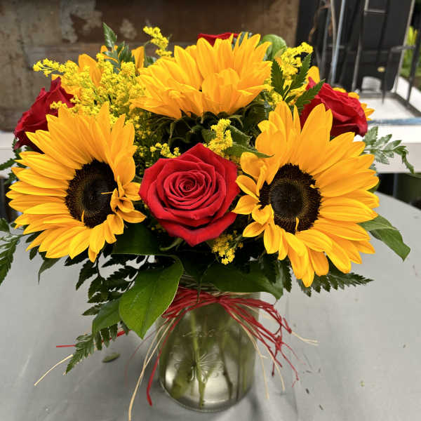 Sunflowers and red roses arranged in a glass vase
