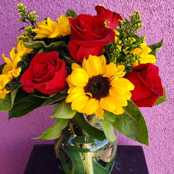 Bouquet of red roses and yellow sunflowers in a glass vase