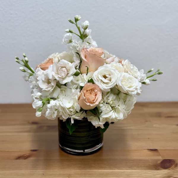 White and peach roses arranged in a black vase
