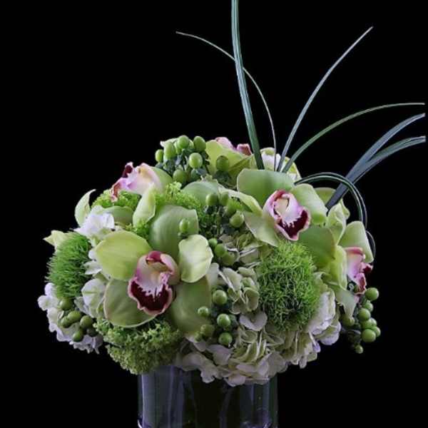 Green and white floral arrangement in a clear glass vase