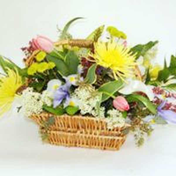 Mixed flower arrangement in a wicker basket with yellow and pink blooms