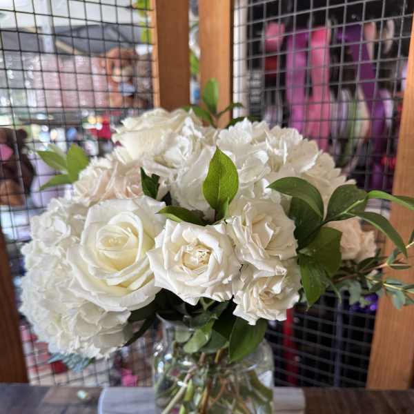 White roses and hydrangeas arranged in a clear glass vase