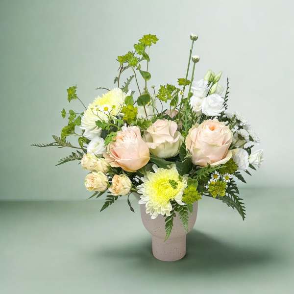 Bouquet of pale peach and white flowers in a pink vase