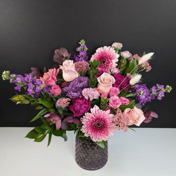 Pink and purple mixed bouquet in a textured glass vase