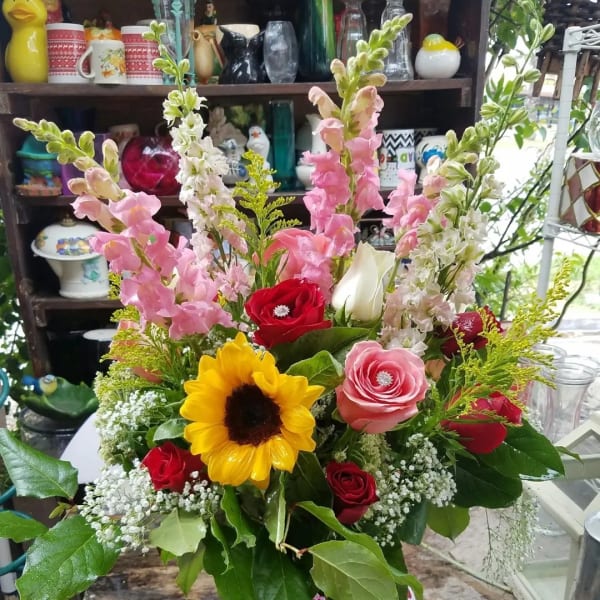 Mixed bouquet in a glass vase with roses, sunflower, and pink snapdragons