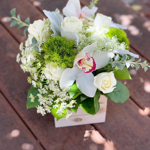 White roses and orchids in a small wooden box