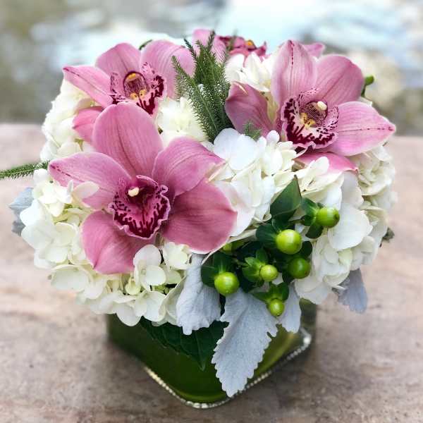 Pink orchids and white hydrangeas in a green glass vase