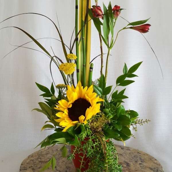 Tall floral arrangement with a sunflower and red alstroemeria in a red vase