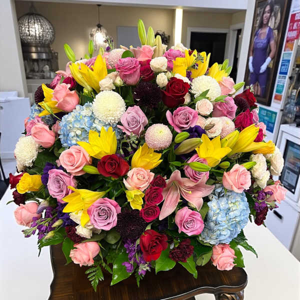 Large mixed bouquet of roses, lilies, and hydrangeas in a dark vase