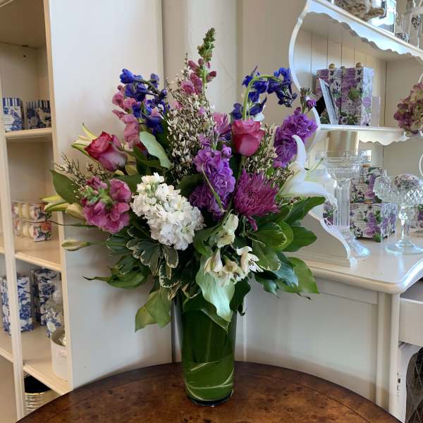 Colorful mixed flower arrangement in a tall glass vase