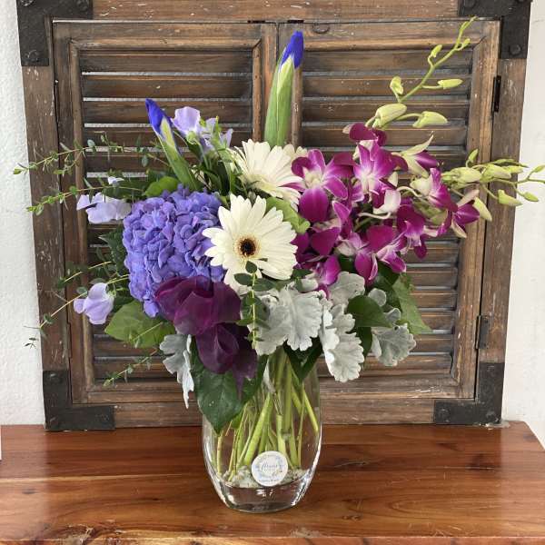 Mixed bouquet in a clear glass vase with purple, white, and pink blooms