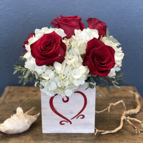 Red roses and white hydrangeas in a white box with a heart design