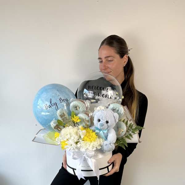 Baby gift arrangement with balloons, flowers, and a teddy bear in a white box