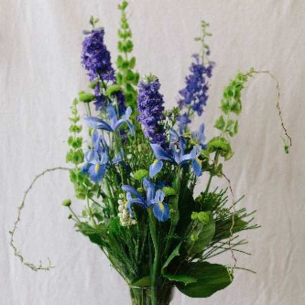 Tall blue and purple floral arrangement in a clear glass vase