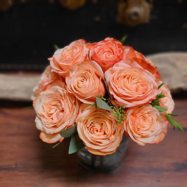 Bouquet of peach roses in a dark vase