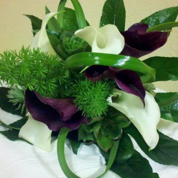 Bouquet of white and dark purple calla lilies with green foliage