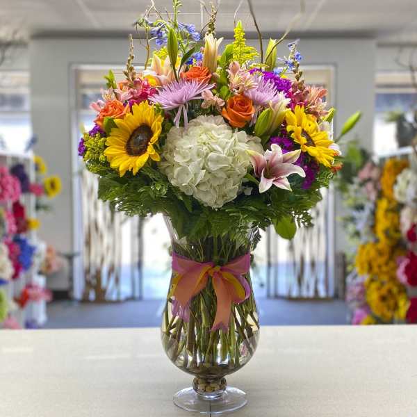Colorful mixed bouquet in a clear glass vase with a ribbon