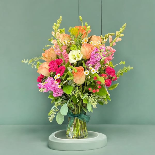 Mixed bouquet of peach and pink roses in a glass vase