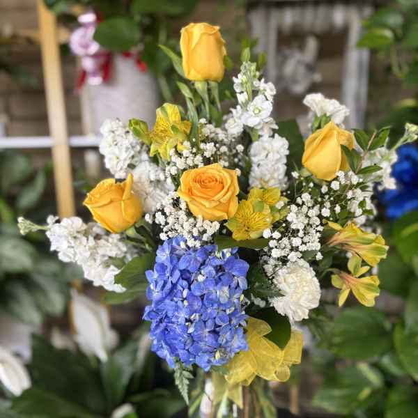 Yellow roses and blue hydrangea in a glass vase