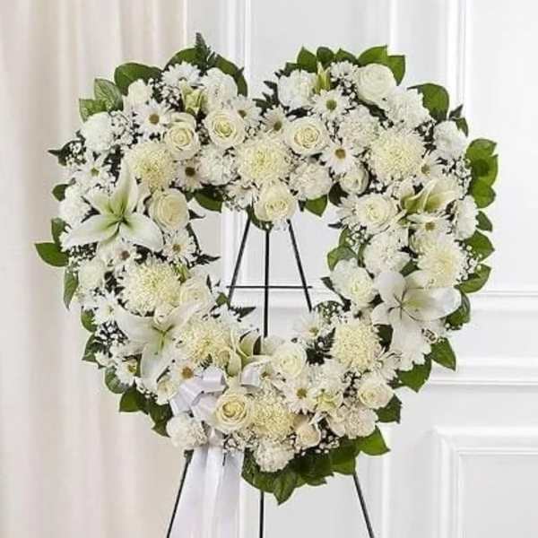 White floral heart wreath on a black stand with a ribbon
