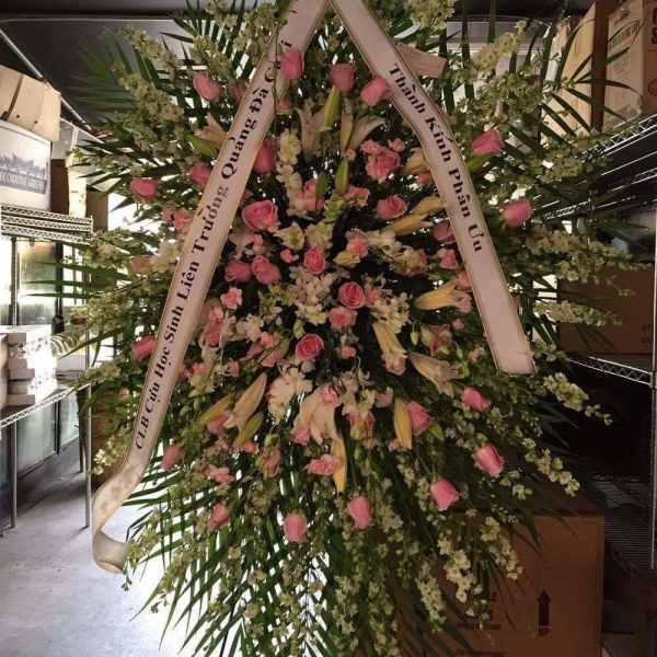 Large standing floral wreath with pink roses and white lilies on a ribboned frame