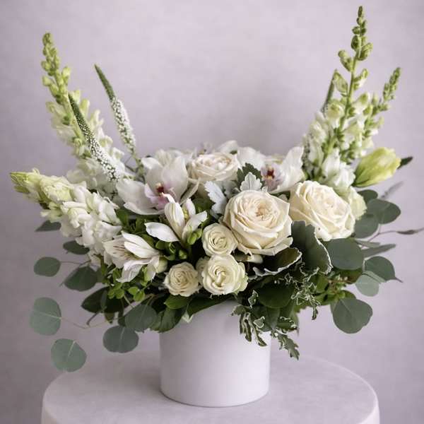 White rose and orchid arrangement in a white cylindrical vase