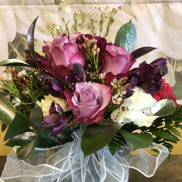 Bouquet of pink and purple roses with white carnations in a glass vase