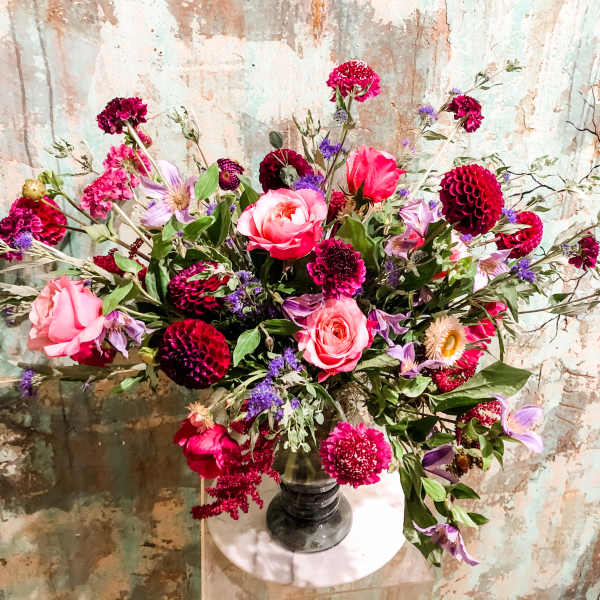 Large mixed bouquet of pink and purple flowers in a dark vase