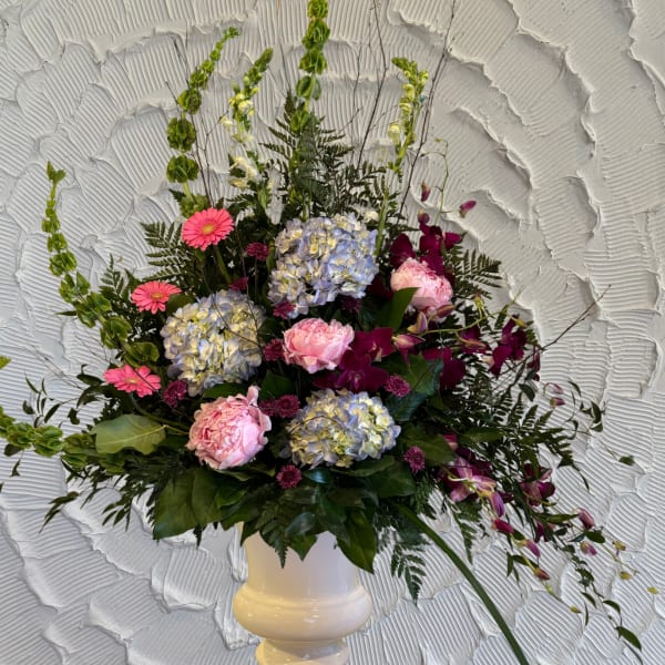 Mixed floral arrangement in a white pedestal vase with pink and purple blooms