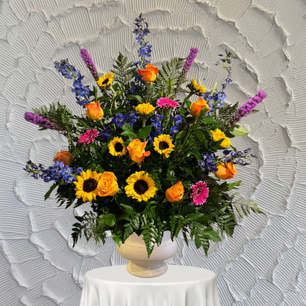 Colorful mixed flower arrangement in a cream vase