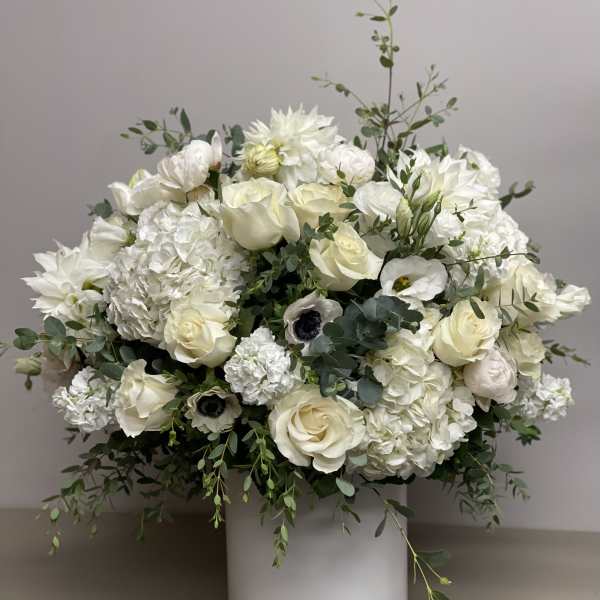 Large white and cream flower arrangement in a white cylinder vase