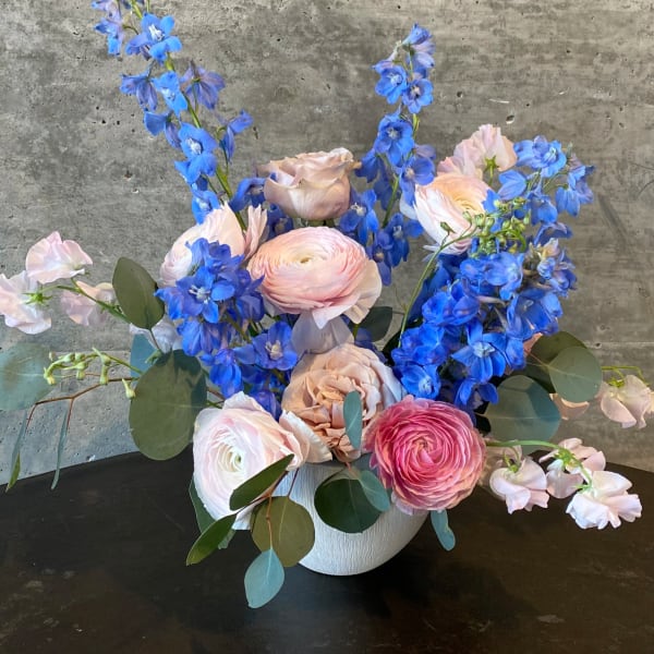 Pink and blue flowers arranged in a white vase