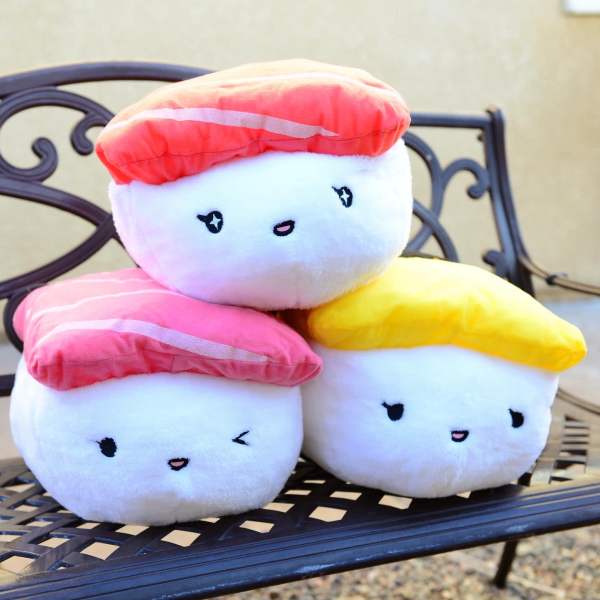 Three plush sushi-shaped pillows stacked on a bench