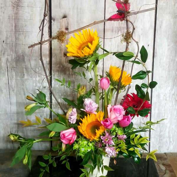 Tall mixed bouquet with sunflowers, pink roses, and gerbera daisies in a white vase