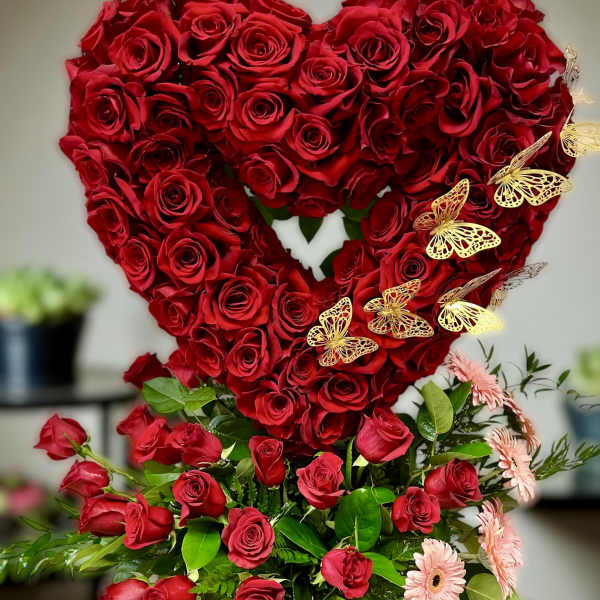 Tall arrangement of red roses in a heart shape with pink gerbera daisies in a black box