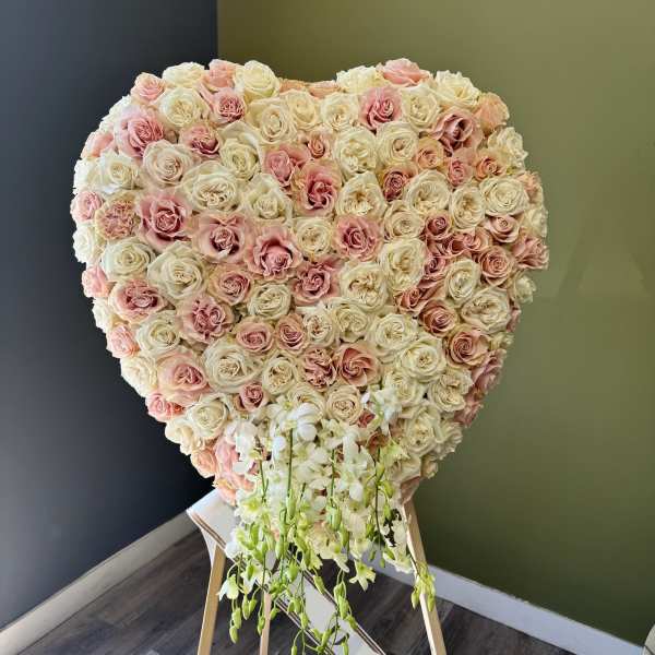Heart-shaped rose arrangement with white orchids on a stand