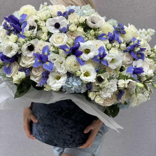 Large bouquet of white and blue flowers held in front of a person