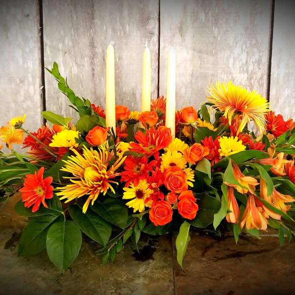 Orange and yellow floral centerpiece with three taper candles