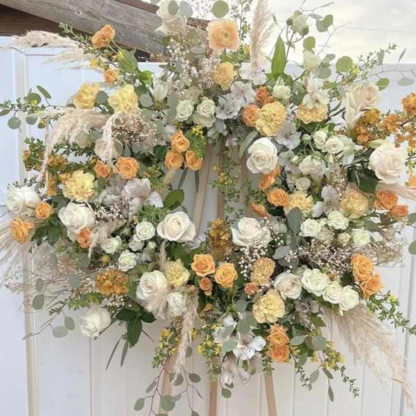 Large floral wreath with white and peach roses on an easel