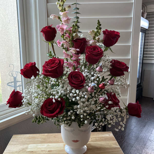 Red roses and pink snapdragons in a white vase