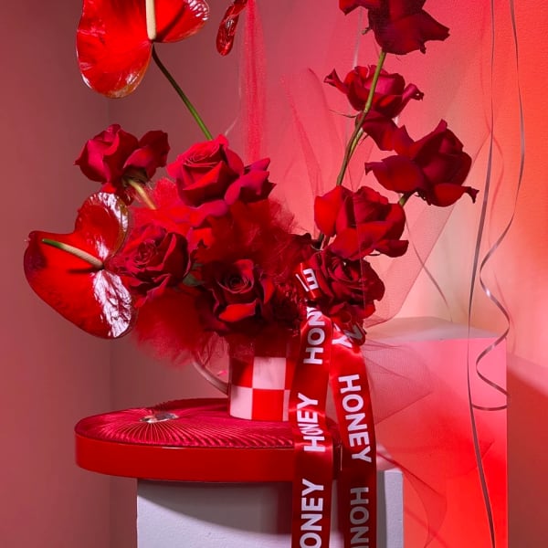 Red roses with heart-shaped anthuriums and a honey ribbon in a gift box