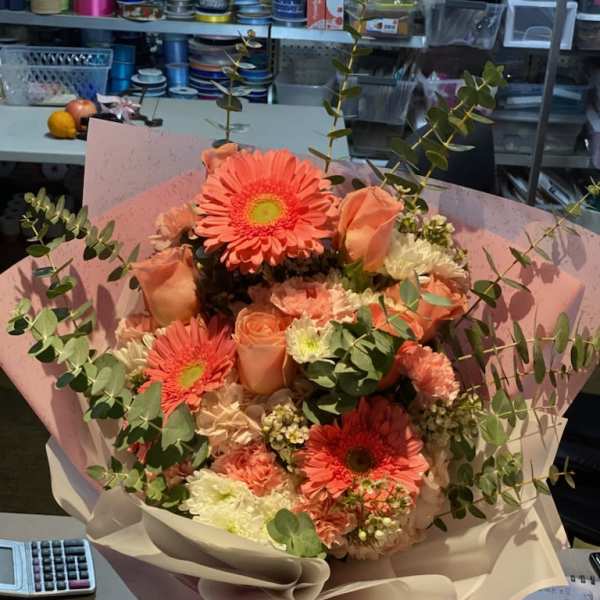 Peach bouquet with gerbera daisies and roses wrapped in pink paper