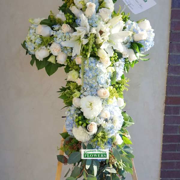 Standing cross-shaped spray of white and pale blue flowers on an easel