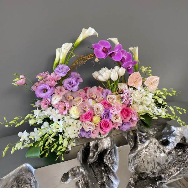 Large floral arrangement with pink, purple, and white blooms in a decorative container