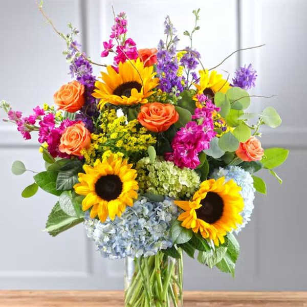 Mixed bouquet with sunflowers, roses, and hydrangeas in a glass vase