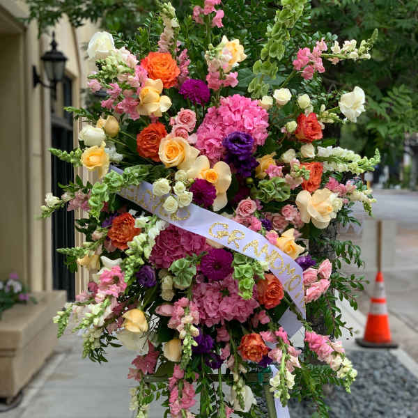 Large standing floral spray with pink, orange, yellow, and white blooms on an easel.