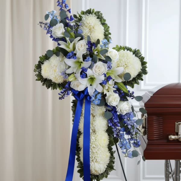 White and blue funeral spray with lilies and roses on a stand
