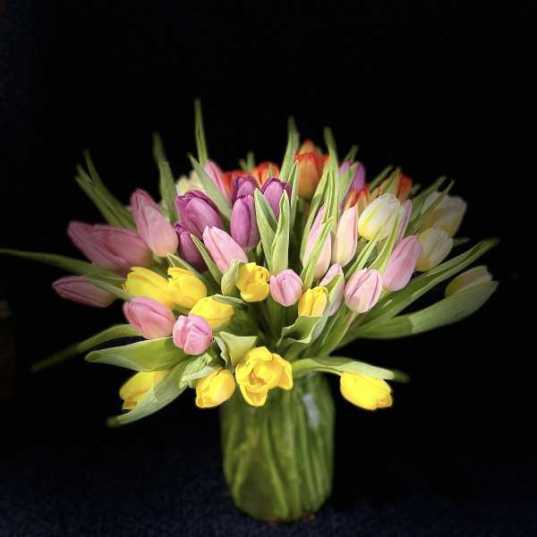 Bouquet of pink, yellow, and purple tulips in a glass vase